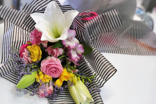 flower bouquet, lily, roses, freesia, mixed flowers, floral arrangement, striped wrapping, romantic gift, colorful flowers, flower closeup, spring bouquet, elegant bouquet, florist design, beautiful flowers, celebration flowers, fresh flowers, flower gift, wedding bouquet, natural beauty, blooming flowers, love and romance, anniversary gift, soft petals, floral texture, gift for her. Winter delivery logistics for Manitoba and Saskatchewan florists
